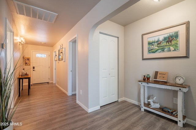 entrance foyer with visible vents, arched walkways, baseboards, and wood finished floors