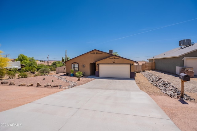 ranch-style house with fence, a garage, stucco siding, central AC unit, and driveway