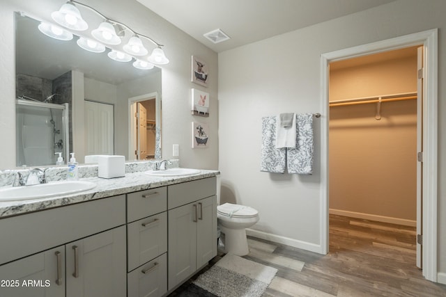 full bathroom with visible vents, a shower stall, a sink, and wood finished floors