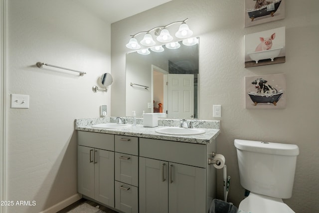 full bathroom with a sink, toilet, and double vanity