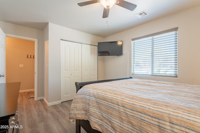 bedroom featuring a closet, visible vents, wood finished floors, baseboards, and ceiling fan