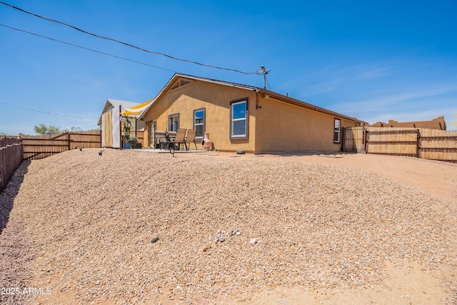 rear view of property with a fenced backyard, a patio area, and stucco siding