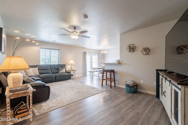 living area featuring plenty of natural light, ceiling fan with notable chandelier, and wood finished floors