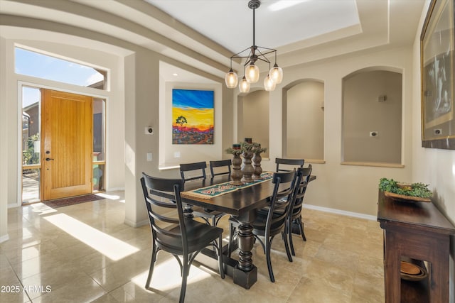 dining room featuring a raised ceiling, light tile patterned flooring, and a notable chandelier