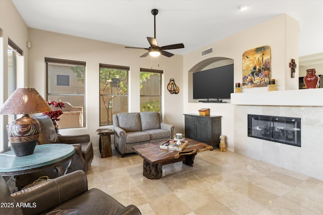 living room featuring ceiling fan and a tiled fireplace