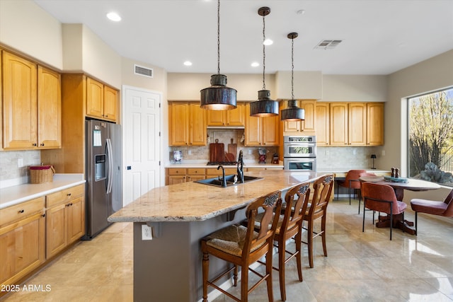 kitchen featuring pendant lighting, a kitchen island with sink, sink, and stainless steel appliances