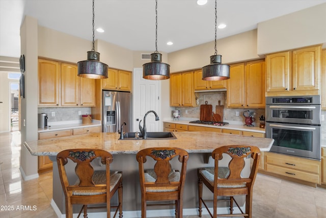 kitchen featuring decorative backsplash, stainless steel appliances, a kitchen island with sink, and sink