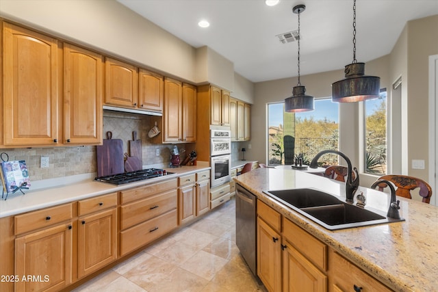 kitchen with backsplash, light stone counters, stainless steel appliances, sink, and decorative light fixtures