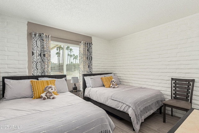 bedroom featuring brick wall, hardwood / wood-style floors, and a textured ceiling