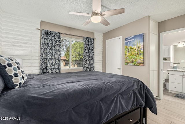 bedroom with ceiling fan, light hardwood / wood-style flooring, a textured ceiling, and ensuite bathroom