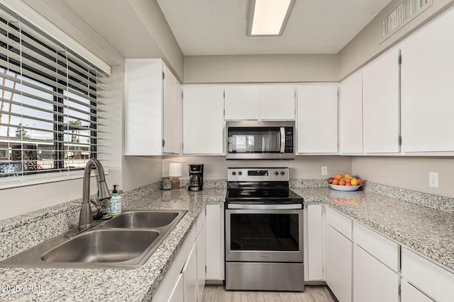 kitchen with stainless steel appliances, light hardwood / wood-style floors, sink, and white cabinets