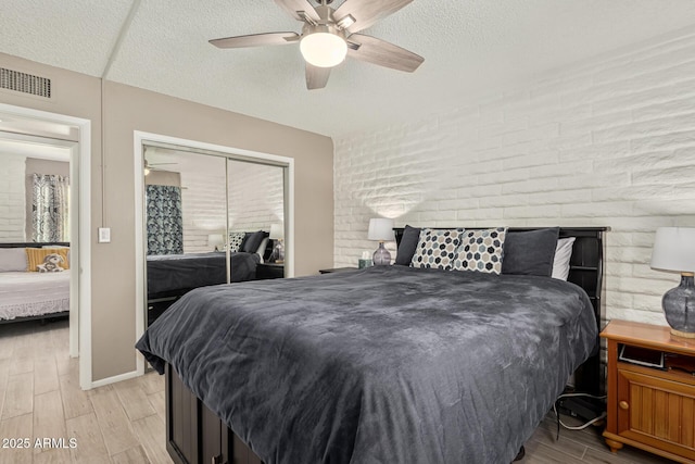 bedroom featuring ceiling fan, a closet, a textured ceiling, and light wood-type flooring