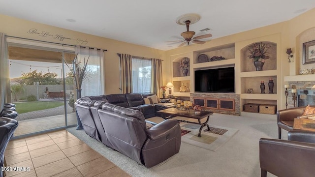 living room with light tile patterned floors, a fireplace, built in features, and ceiling fan