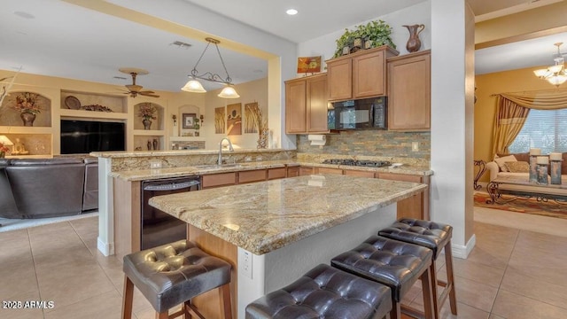 kitchen featuring kitchen peninsula, decorative light fixtures, sink, a breakfast bar area, and black appliances