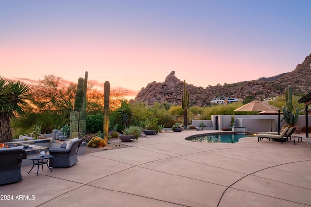 pool at dusk featuring a mountain view and a patio area