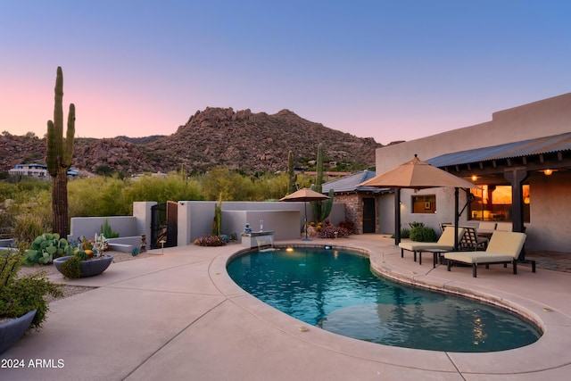 pool at dusk with a mountain view and a patio