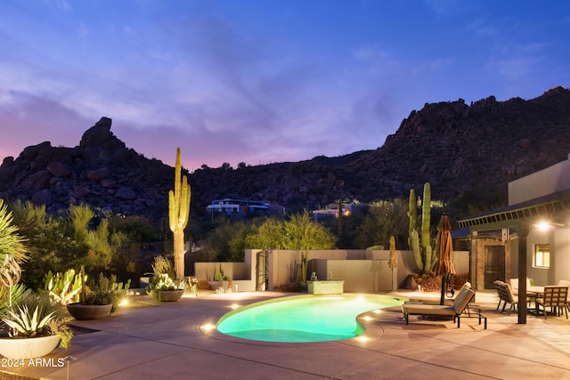 pool at dusk with a mountain view and a patio