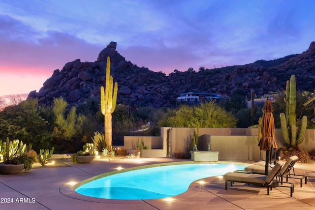 pool at dusk with a mountain view and a patio area