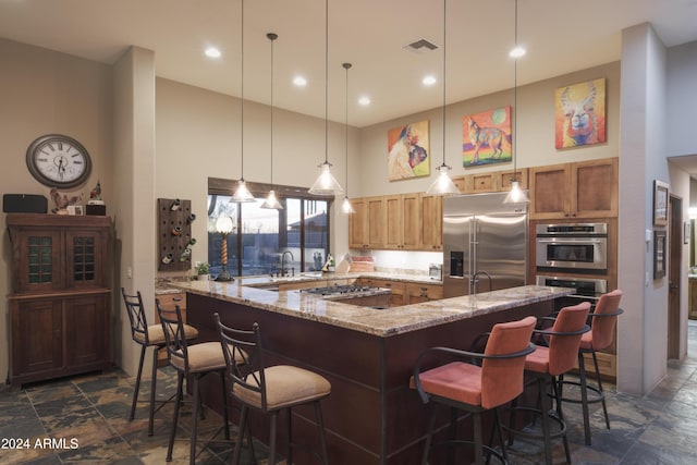 kitchen featuring light stone countertops, sink, hanging light fixtures, a kitchen bar, and appliances with stainless steel finishes