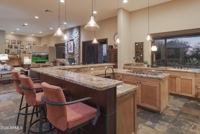 kitchen featuring a kitchen bar, sink, pendant lighting, and stainless steel gas cooktop