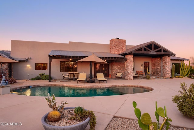 pool at dusk featuring a patio