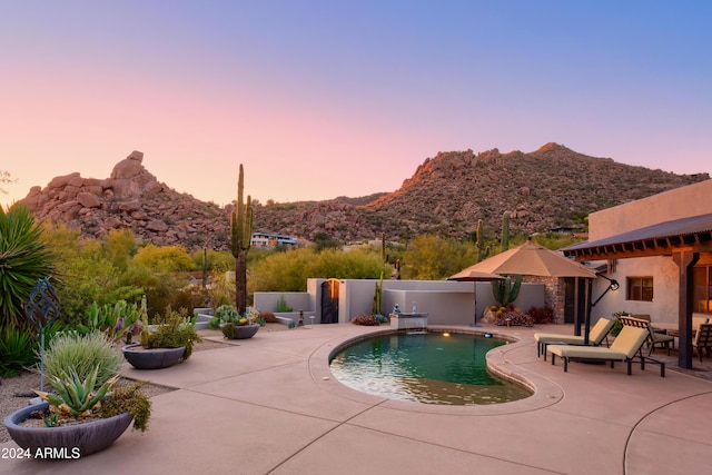 pool at dusk with a mountain view and a patio