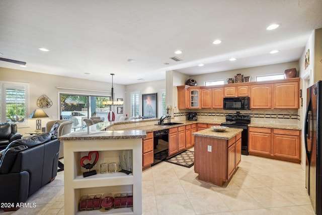 kitchen featuring pendant lighting, black appliances, tasteful backsplash, a kitchen island, and kitchen peninsula