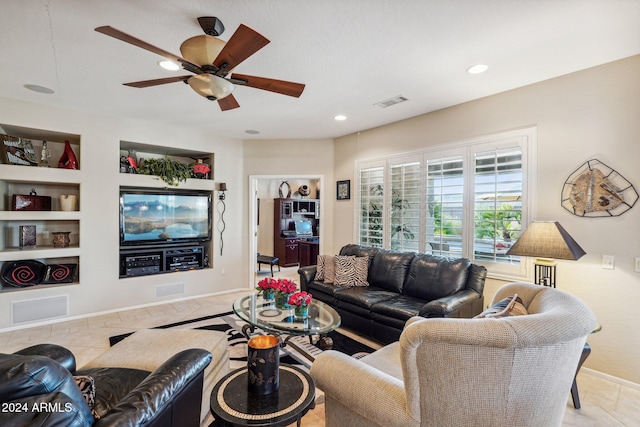 living room with built in shelves, ceiling fan, and light tile patterned floors