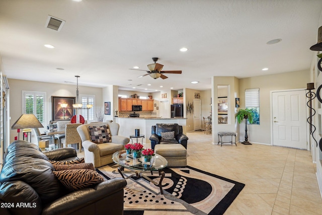 living room featuring ceiling fan with notable chandelier and light tile patterned floors