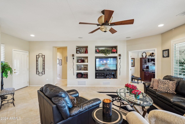 tiled living room with ceiling fan and built in features