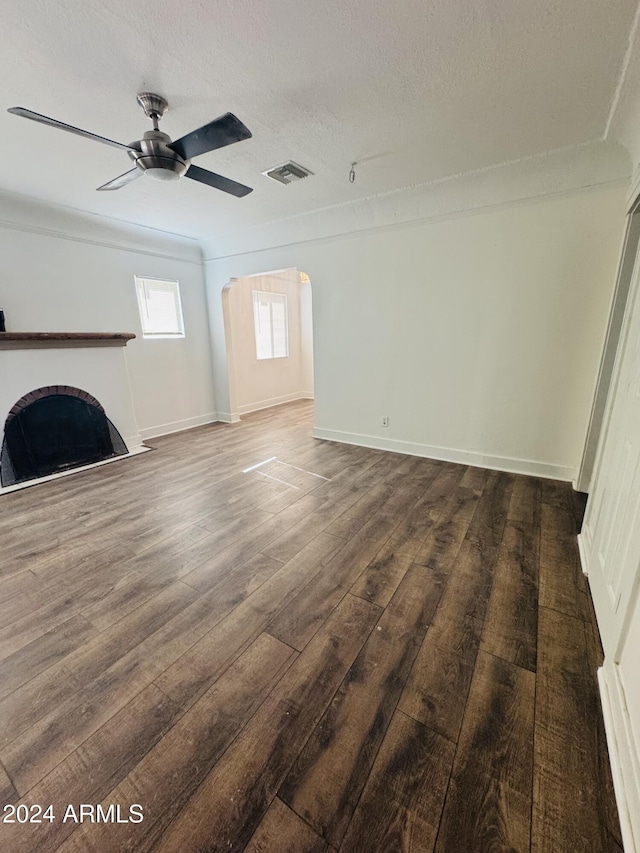 unfurnished living room featuring ceiling fan, dark hardwood / wood-style flooring, and a textured ceiling