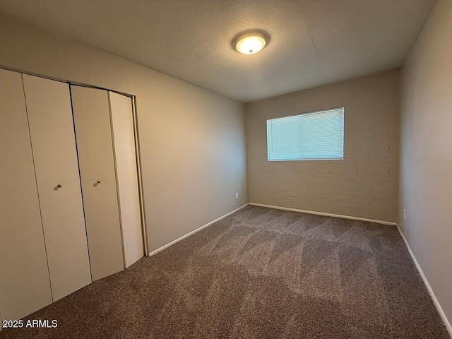unfurnished bedroom featuring a closet, carpet flooring, a textured ceiling, and baseboards
