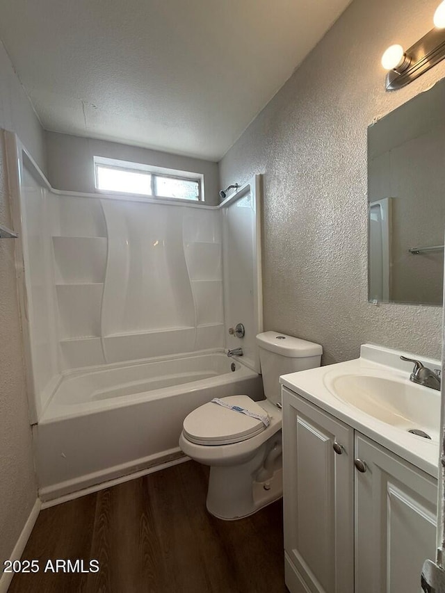 full bath featuring shower / bathing tub combination, vanity, toilet, a textured wall, and wood finished floors