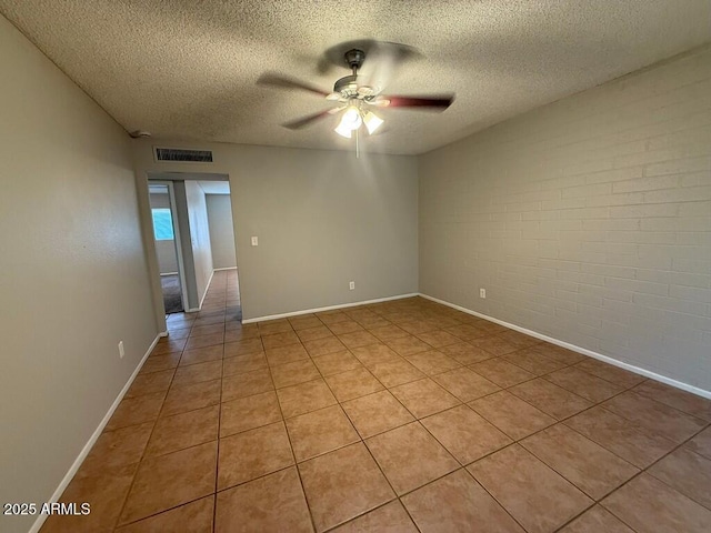 spare room featuring a textured ceiling, visible vents, a ceiling fan, and brick wall