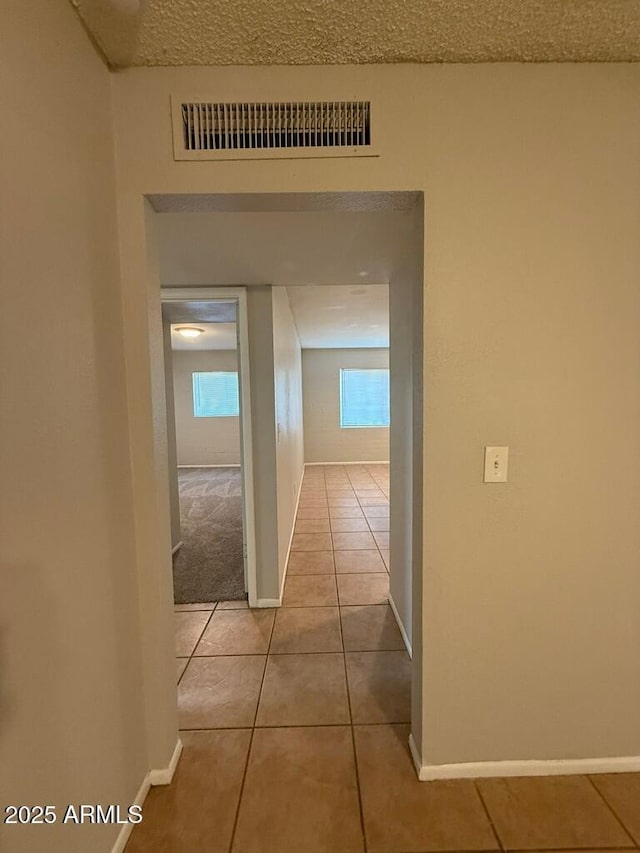 corridor with baseboards, visible vents, and tile patterned flooring
