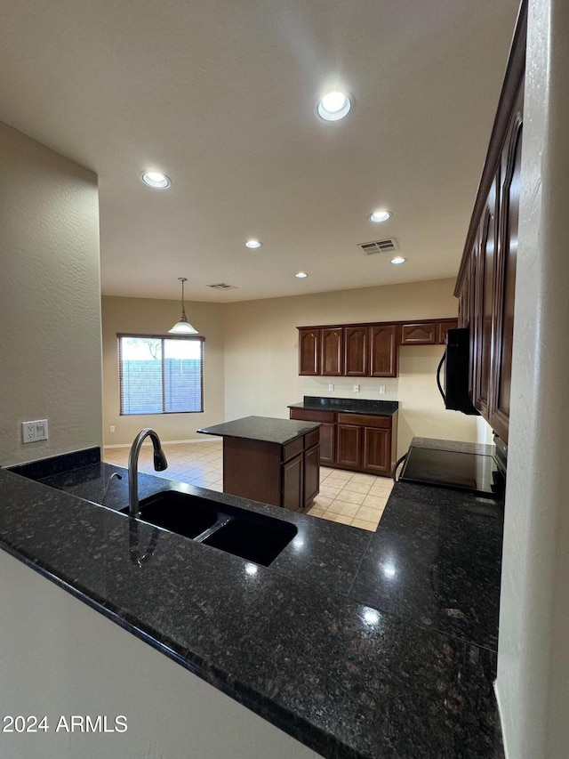 kitchen featuring pendant lighting, black appliances, sink, a kitchen island, and dark brown cabinetry