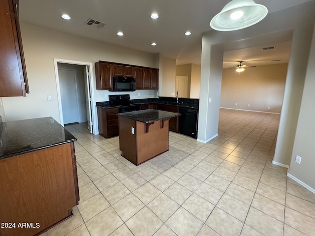 kitchen featuring dark stone counters, ceiling fan, a center island, and black appliances