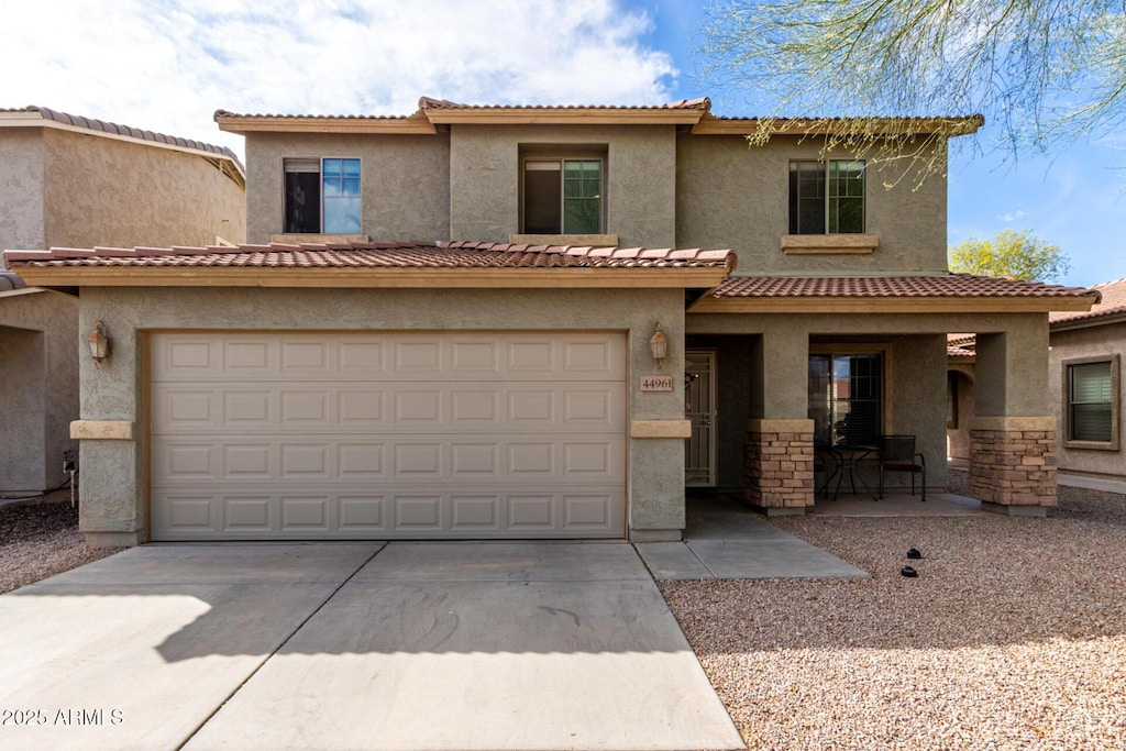 view of front of home with concrete driveway, a tiled roof, and stucco siding