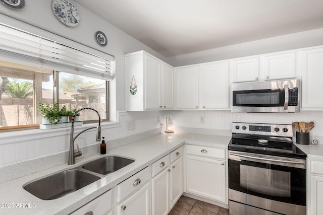 kitchen featuring a sink, white cabinetry, stainless steel appliances, light countertops, and light tile patterned floors