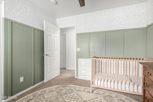 unfurnished bedroom with wallpapered walls, a closet, a nursery area, carpet flooring, and a decorative wall