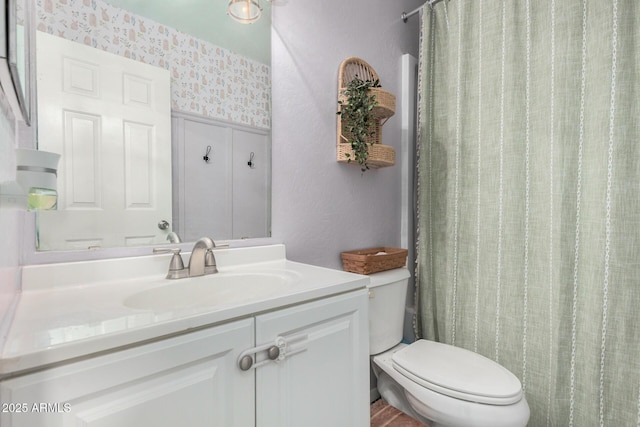 bathroom featuring wallpapered walls, toilet, and vanity