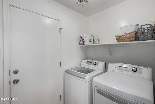 clothes washing area with laundry area, visible vents, and separate washer and dryer