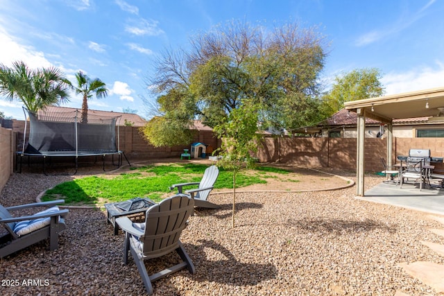 view of yard with a fenced backyard, a patio, an outdoor fire pit, and a trampoline