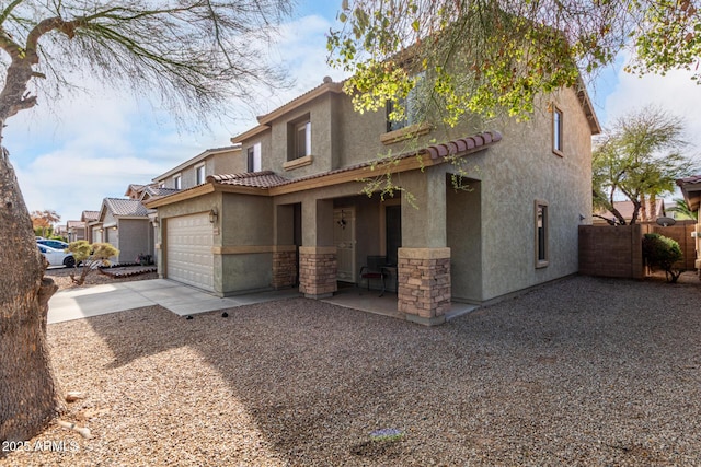 view of front facade featuring fence, a tiled roof, concrete driveway, stucco siding, and an attached garage