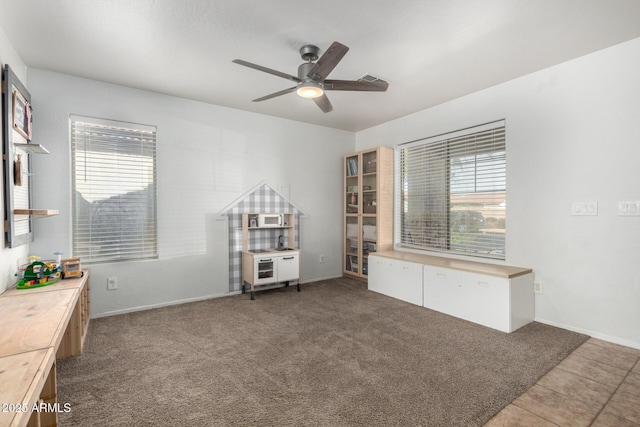 interior space featuring carpet flooring, baseboards, and ceiling fan