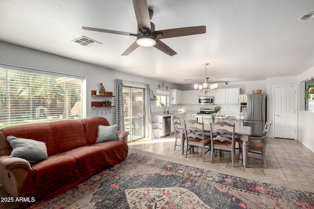 living room with light tile patterned floors, ceiling fan with notable chandelier, and visible vents