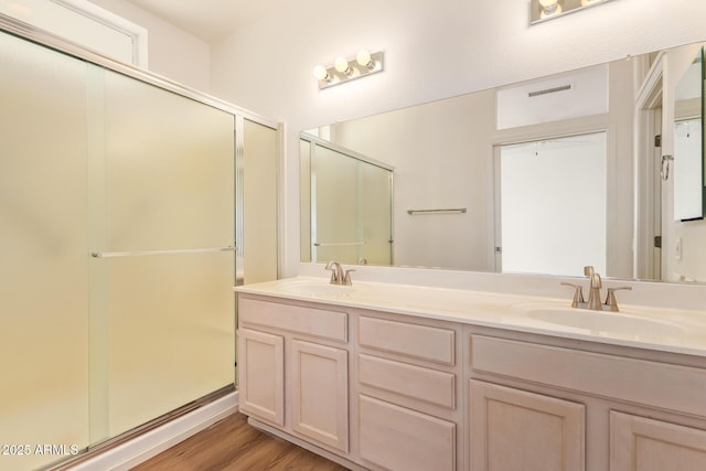 full bath with a sink, a stall shower, wood finished floors, and visible vents
