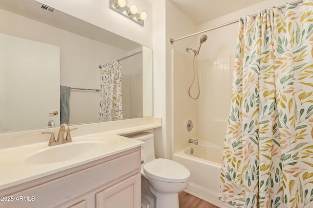 bathroom featuring visible vents, shower / tub combo with curtain, vanity, wood finished floors, and toilet
