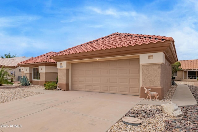 mediterranean / spanish-style home featuring a tiled roof, a garage, driveway, and stucco siding