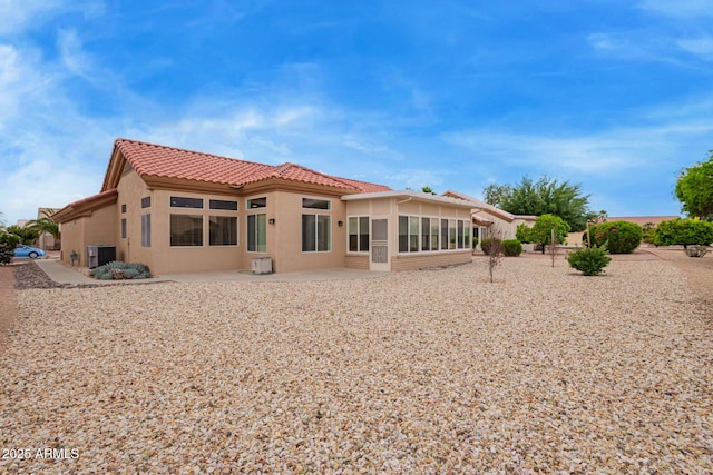 rear view of house with a tiled roof, cooling unit, a patio area, and stucco siding